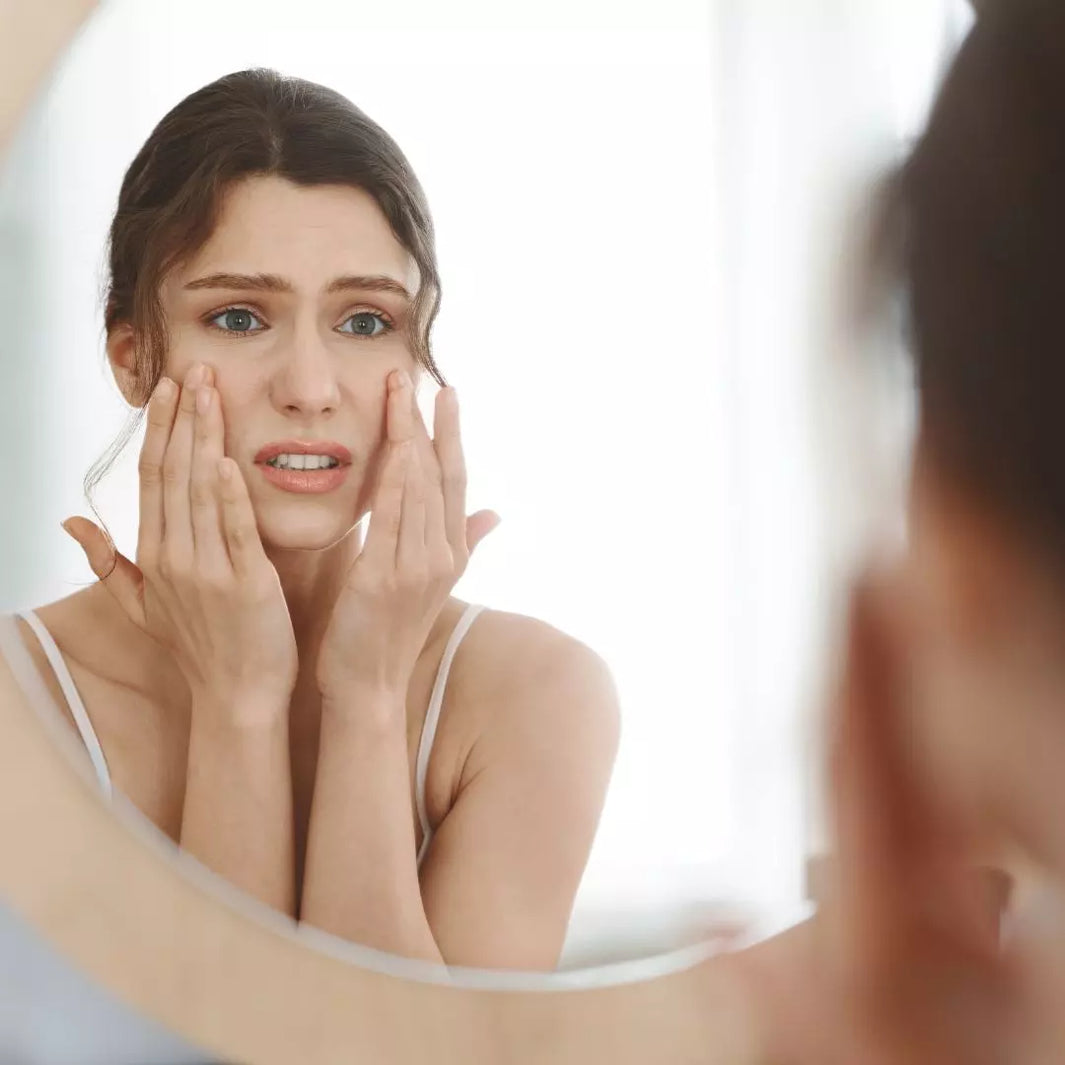 A close-up image of a stressed individual holding their face with visible signs of irritation, acne, or fine lines, paired with calming skincare products on the side.